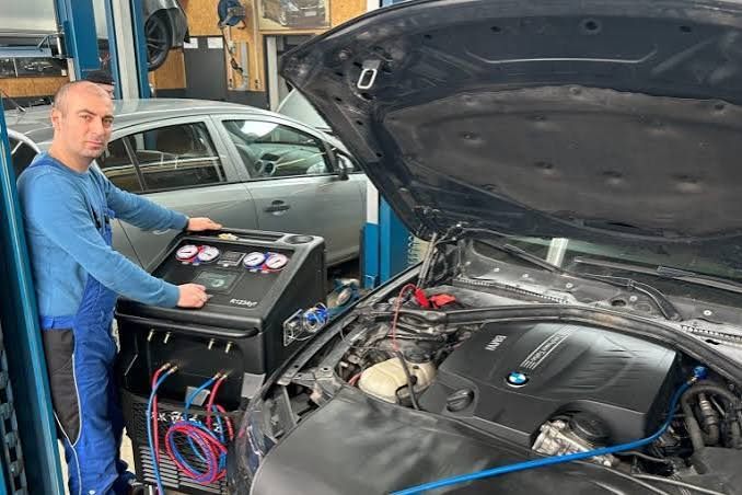 Mitarbeiter bedient das Klimaservicegerät an einem BMW