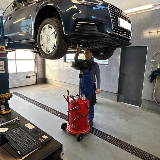 Fahrzeug auf der Hebebühne beim Ölwechsel, daneben das Diagnosegerät