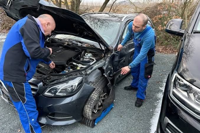 Zwei Mitarbeiter begutachten den Frontschaden an einem Mercedes